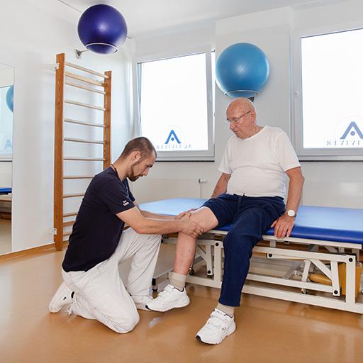 Activiver®-Physiotherapeut in der Behandlung eines Patienten mit Kniebeschwerden, umgeben von Therapiegeräten und Übungsbällen.