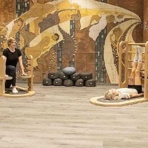 Zwei Personen üben entspannende Yoga-Positionen mit speziellen Holzgeräten in der YOGA ZONE von ACTIVIVER.